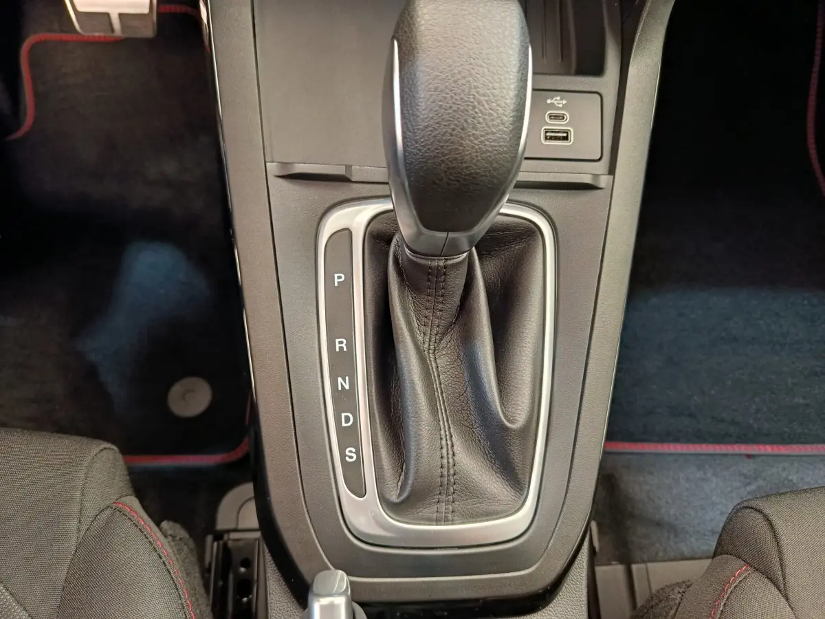 Le levier de vitesses automatique noir avec coutures rouges du Ford Puma 2025 en vue plongeante sur la console centrale.