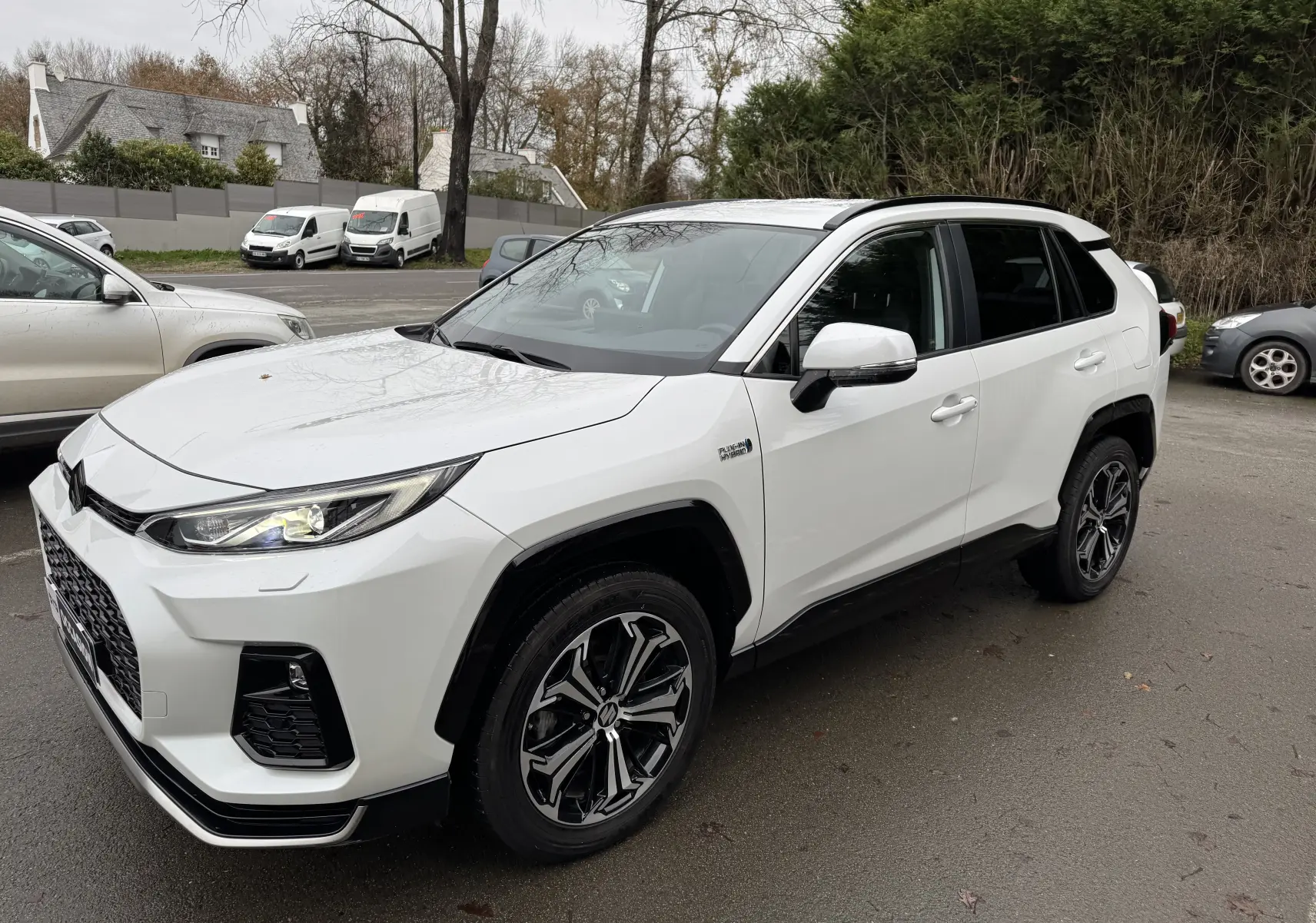 Suzuki Across hybride rechargeable blanc en vue 3/4 avant droit, avec jantes noires et détails noirs contrastants.