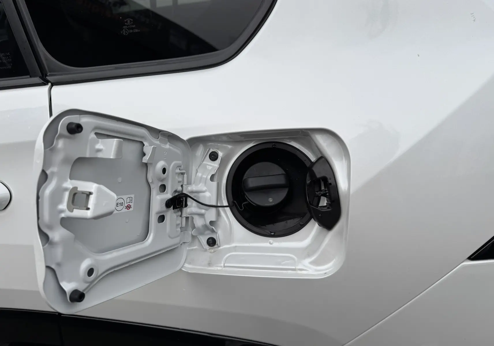 Gros plan sur la trappe de carburant ouverte côté gauche d’un Suzuki Across blanc hybride rechargeable 2023.