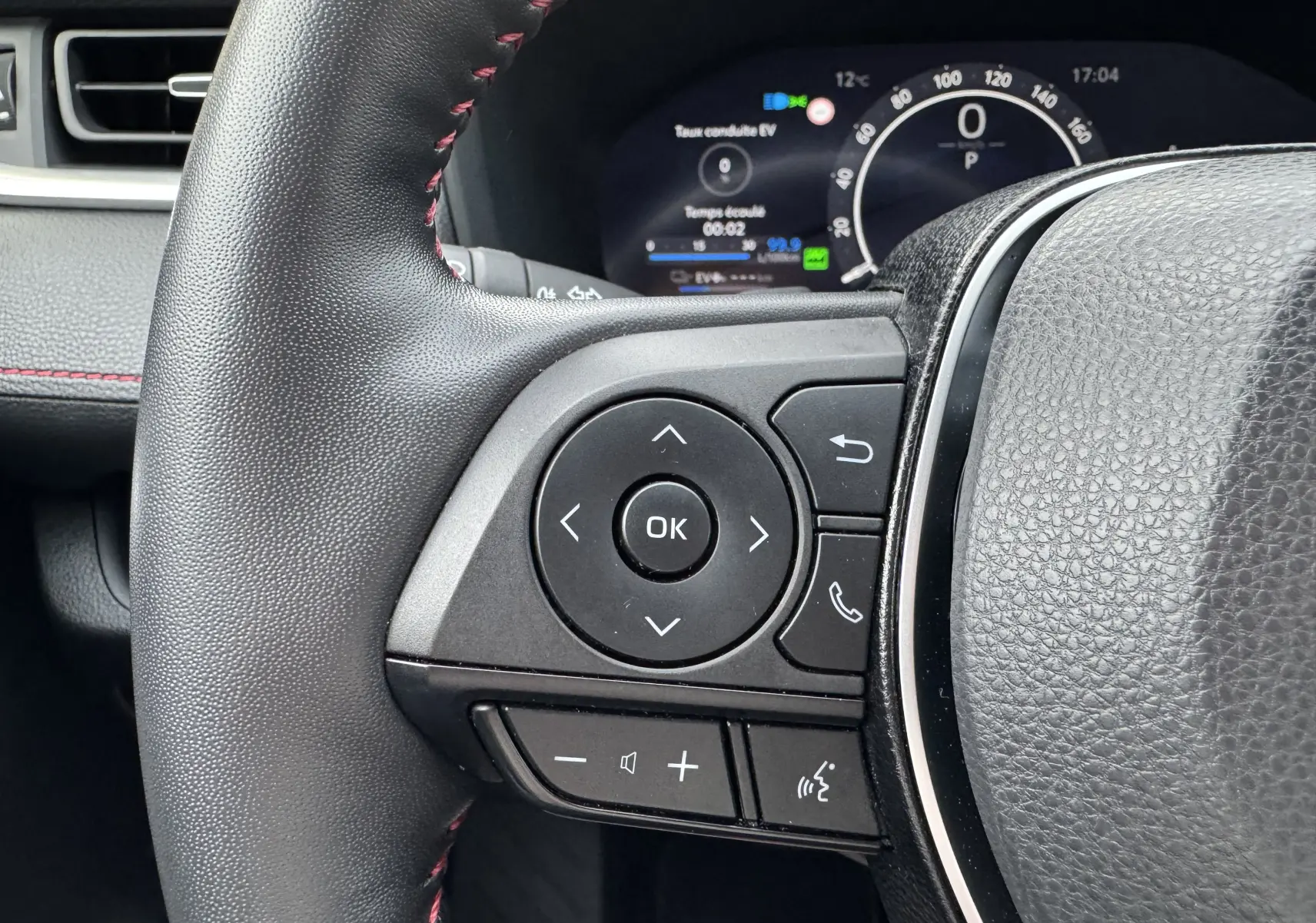 Gros plan sur les commandes gauche du volant cuir noir avec surpiqûres rouges du Suzuki Across hybride rechargeable 2023.