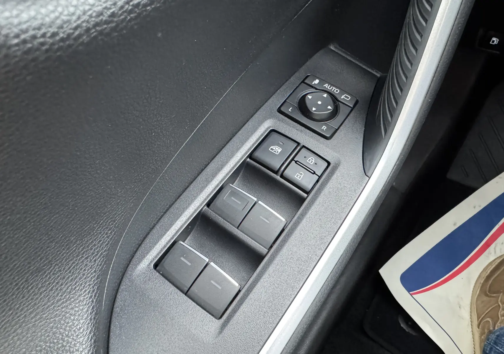 Gros plan sur les commandes des vitres et rétroviseurs côté conducteur du Suzuki Across blanc 2023 hybride rechargeable.