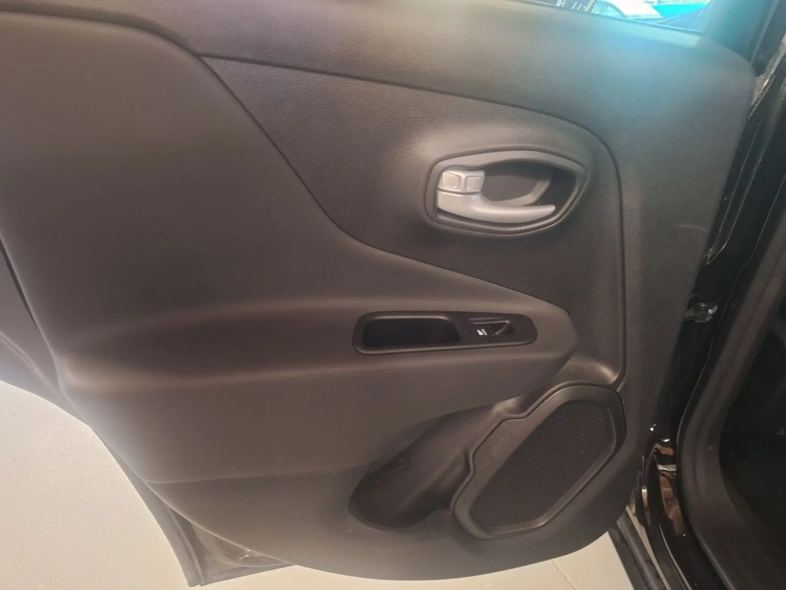 Gros plan sur la porte arrière côté gauche noire du Jeep Renegade 2024 avec poignée et haut-parleur intégrés.