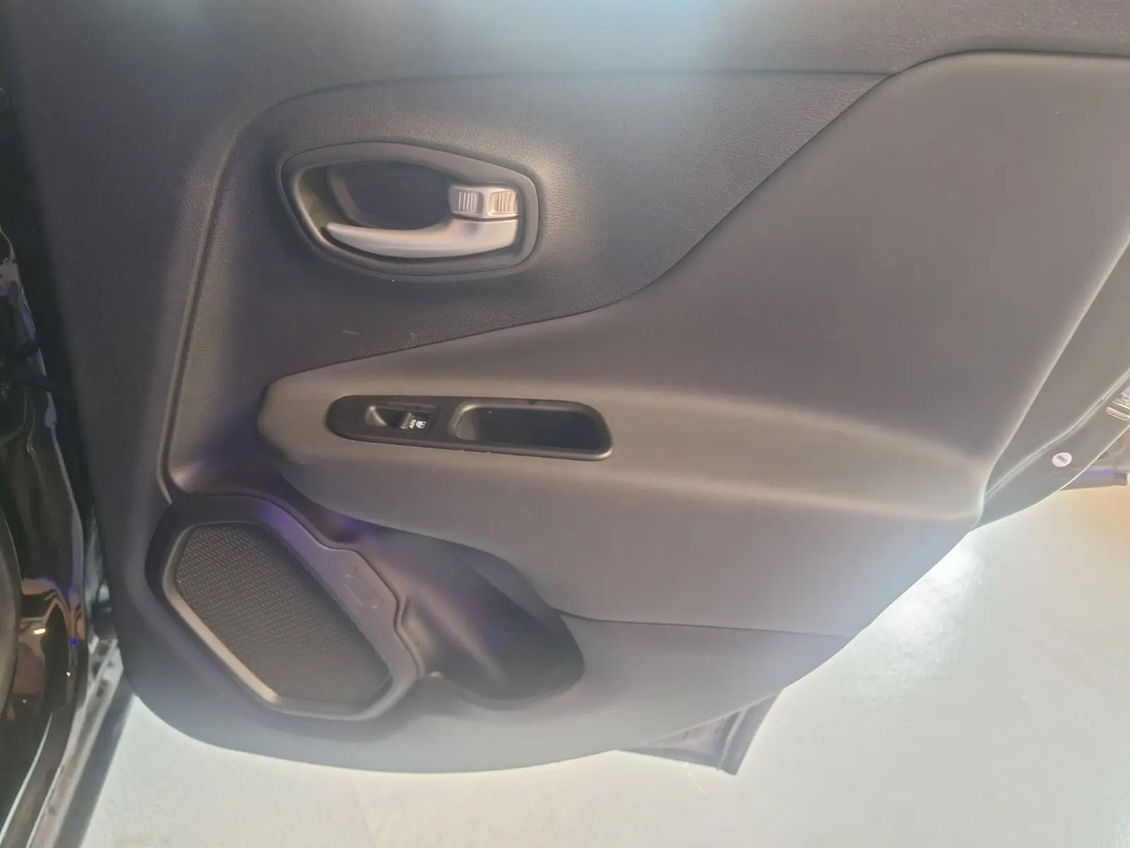 Gros plan sur la porte arrière droite noire d'un Jeep Renegade 2024 avec poignée et haut-parleur intégrés.