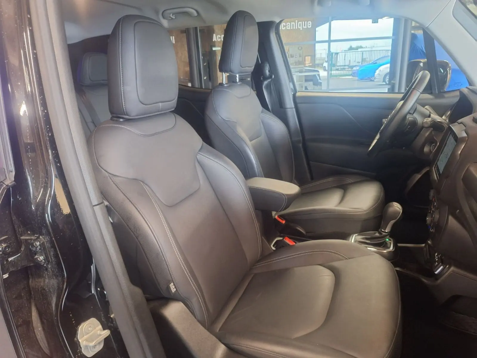 Vue intérieure côté conducteur du Jeep Renegade noir 2024, sièges en cuir noir et console centrale avec boîte automatique.