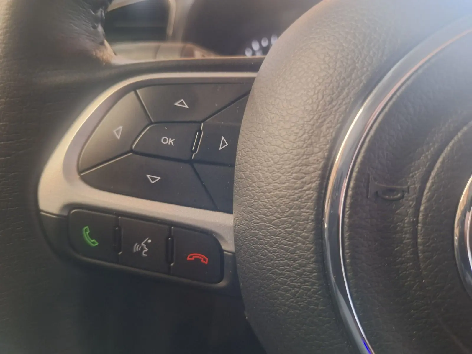 Gros plan sur les commandes multifonctions à gauche du volant noir du Jeep Renegade 2024 hybride.