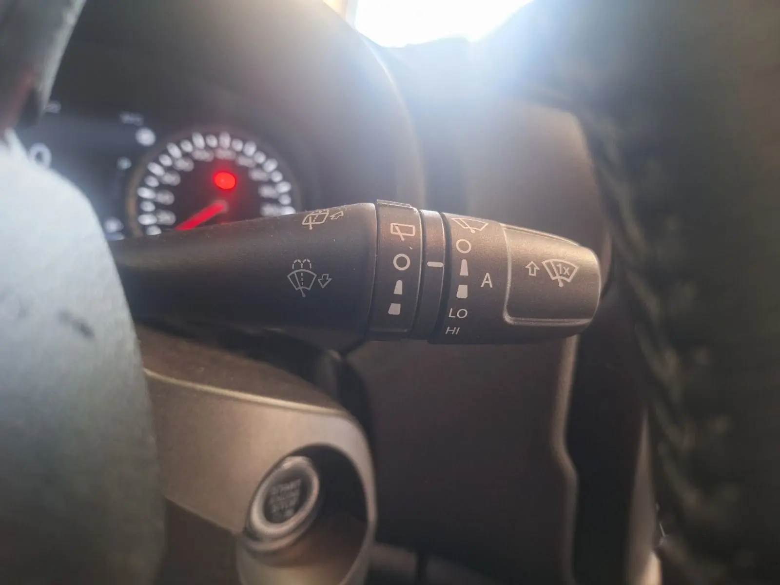 Gros plan sur le commodo d'essuie-glace à gauche du volant dans l'habitacle noir du Jeep Renegade 2024.