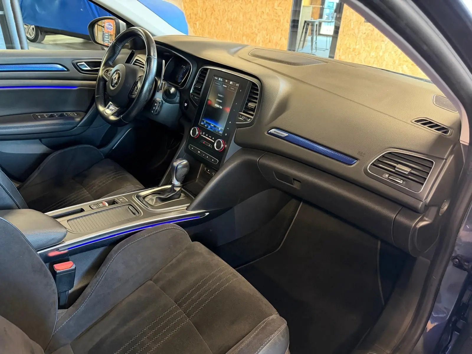 Intérieur avant droit de la Renault Mégane Break GT 2017, avec tableau de bord noir et éclairage d'ambiance bleu.