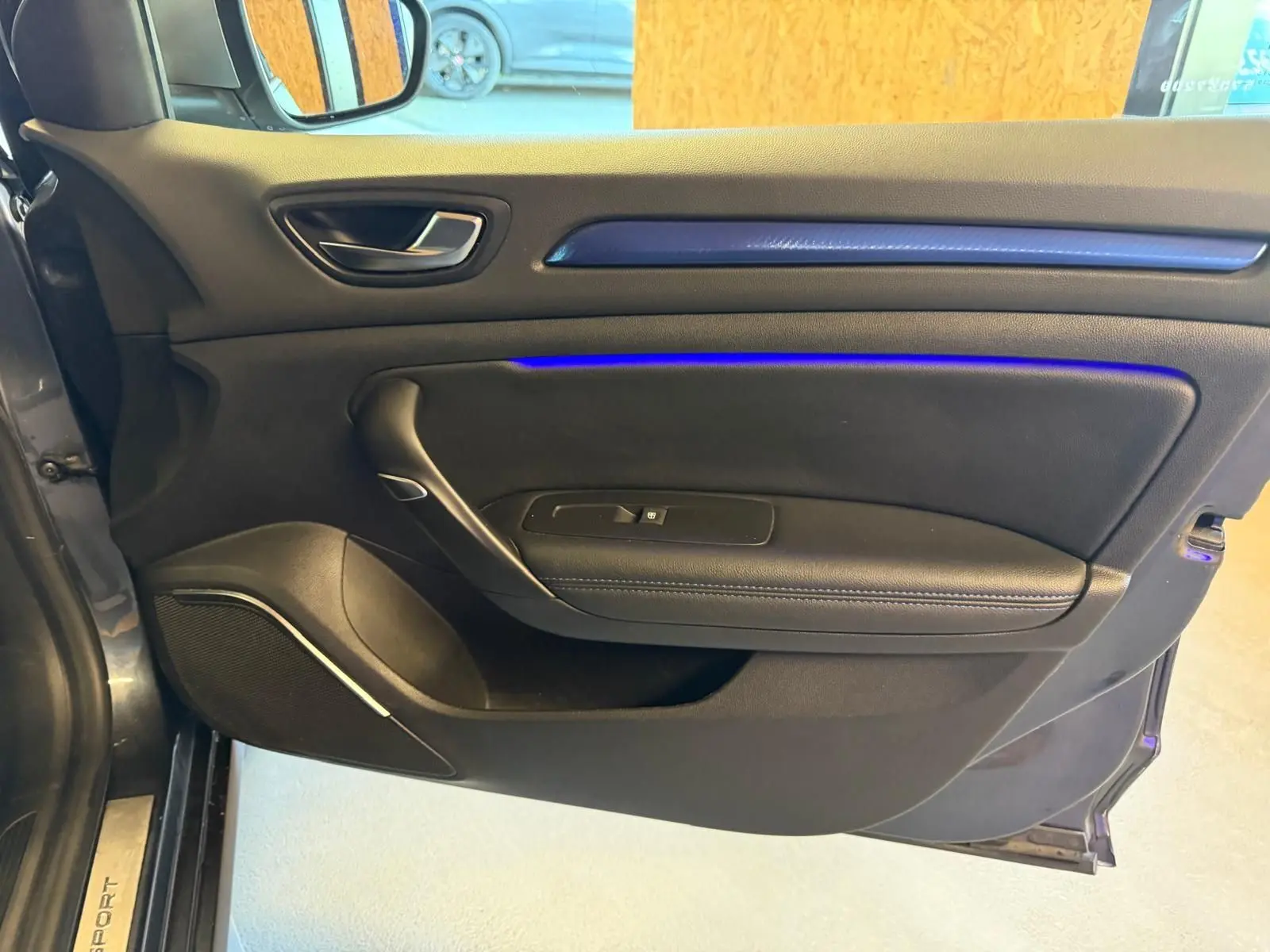 Vue intérieure de la porte avant gauche de la Renault Mégane Break GT gris, avec éclairage d'ambiance bleu subtil.