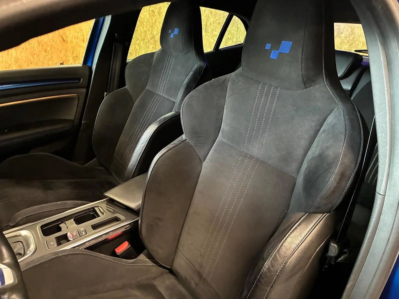 Vue intérieure rapprochée des sièges avant noirs en alcantara avec logo bleu sur appuie-tête d’une Renault Mégane GT Line 2019.