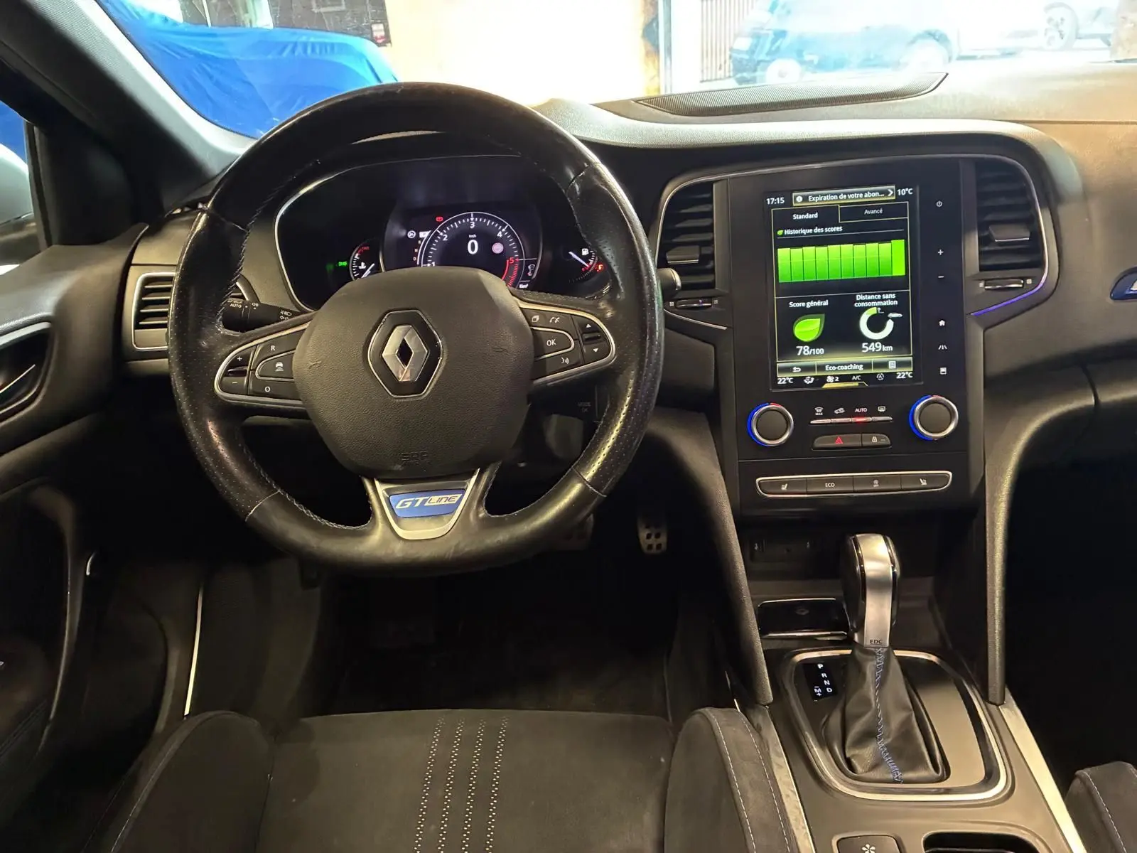 Vue intérieure frontale du poste de conduite d'une Renault Mégane GT Line 2019 avec volant cuir noir et écran tactile central allumé.