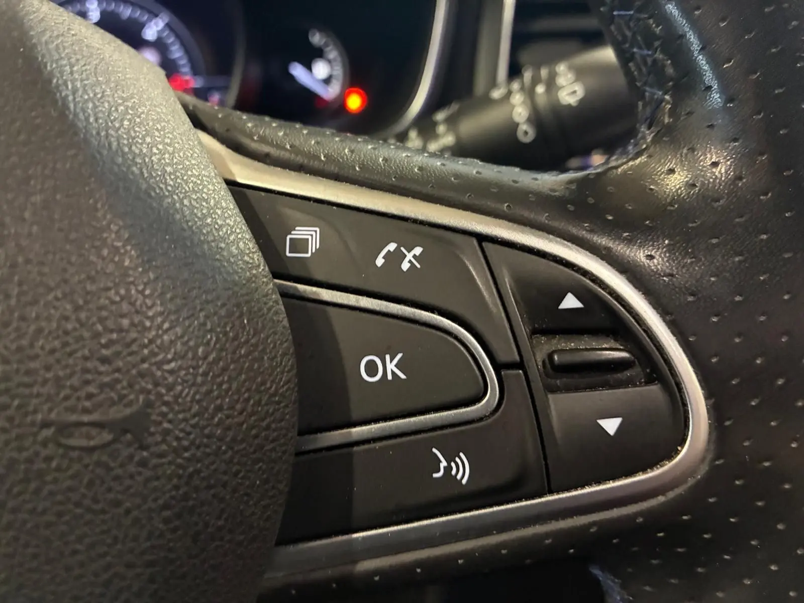 Gros plan sur les commandes multifonctions noires du volant perforé d’une Renault Mégane 1.7 BlueDCI 150 GT Line 2019.