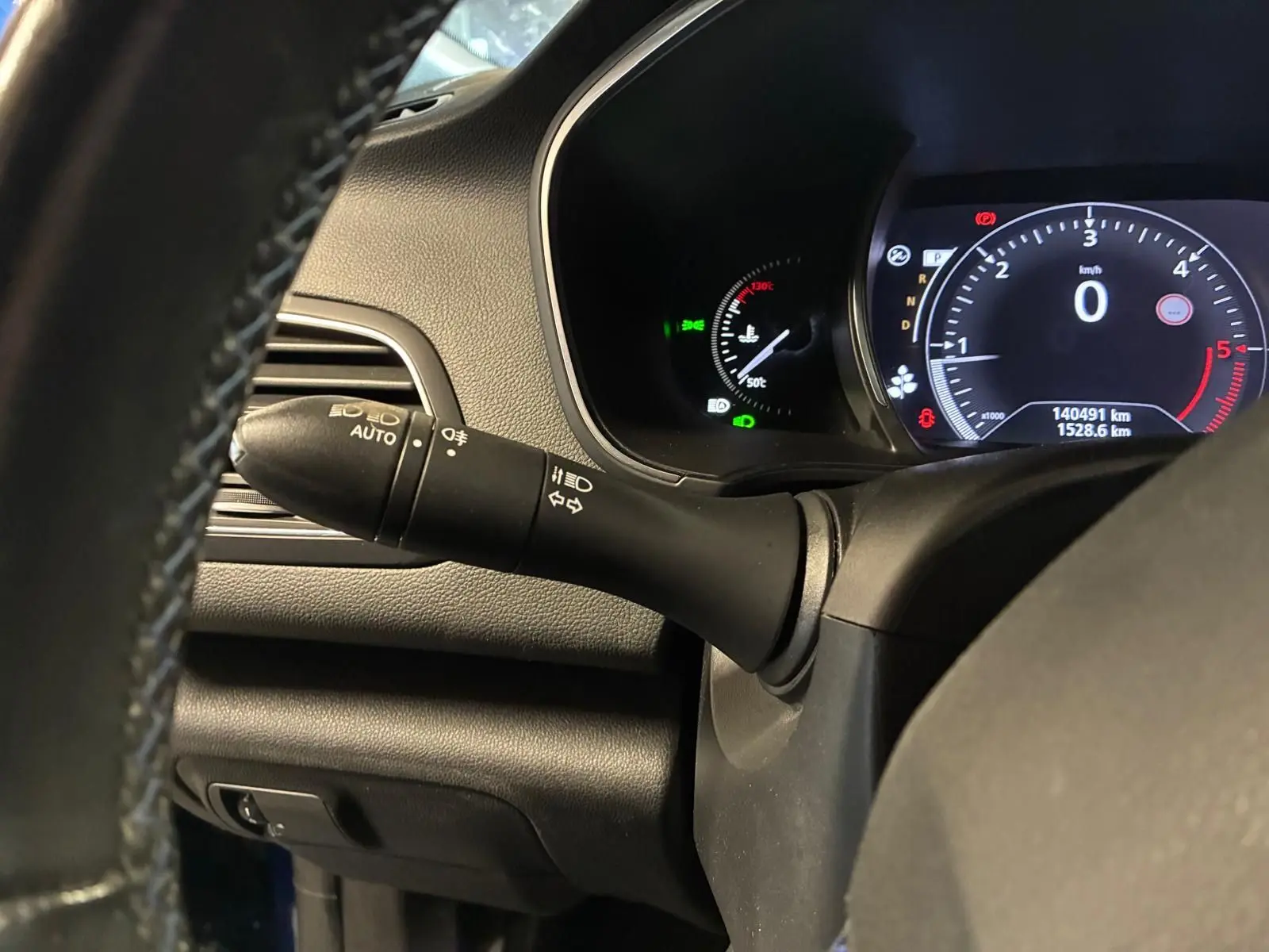 Vue rapprochée du commodo d’éclairage et du tableau de bord numérique d’une Renault Mégane bleu 2019.