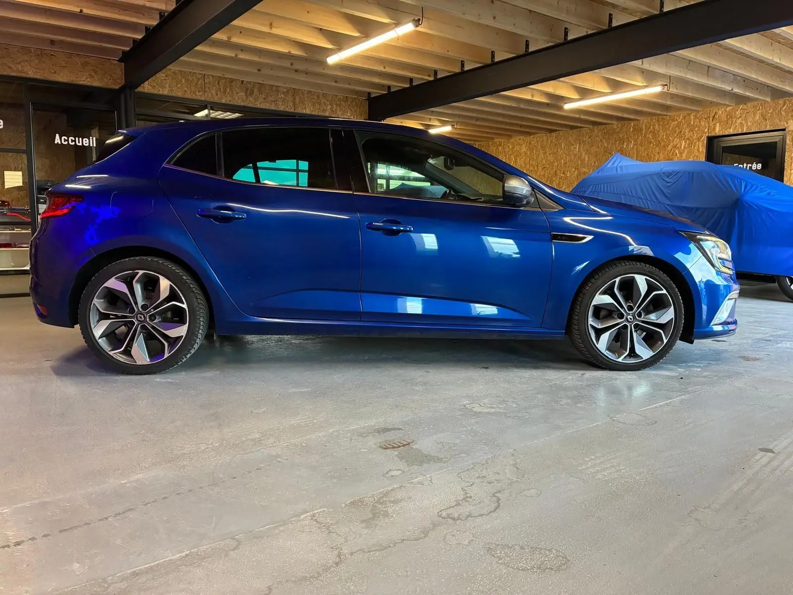 Renault Mégane 1.7 BlueDCI 150 GT Line bleu vue de profil côté gauche dans un garage intérieur.