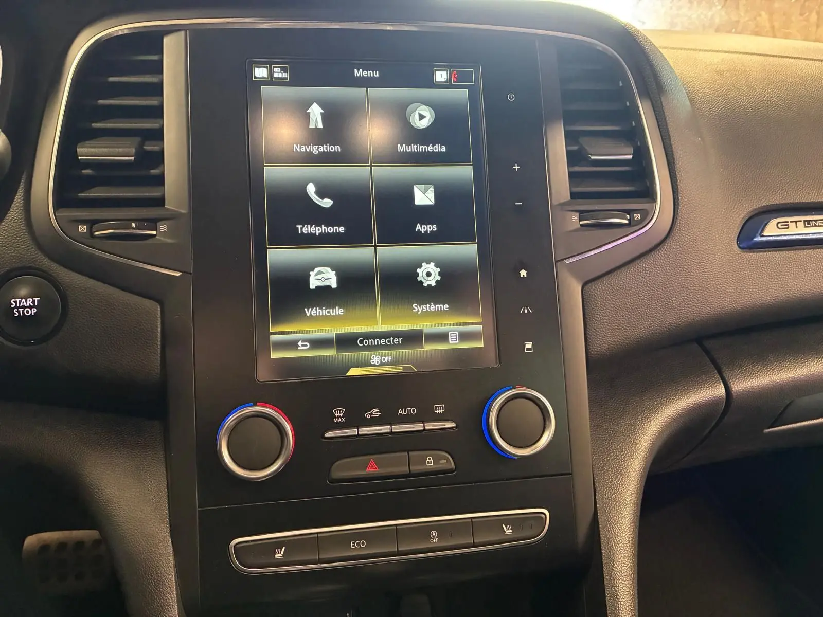 Vue rapprochée du tableau de bord noir de la Renault Mégane GT Line 2019 avec écran tactile et commandes de climatisation.