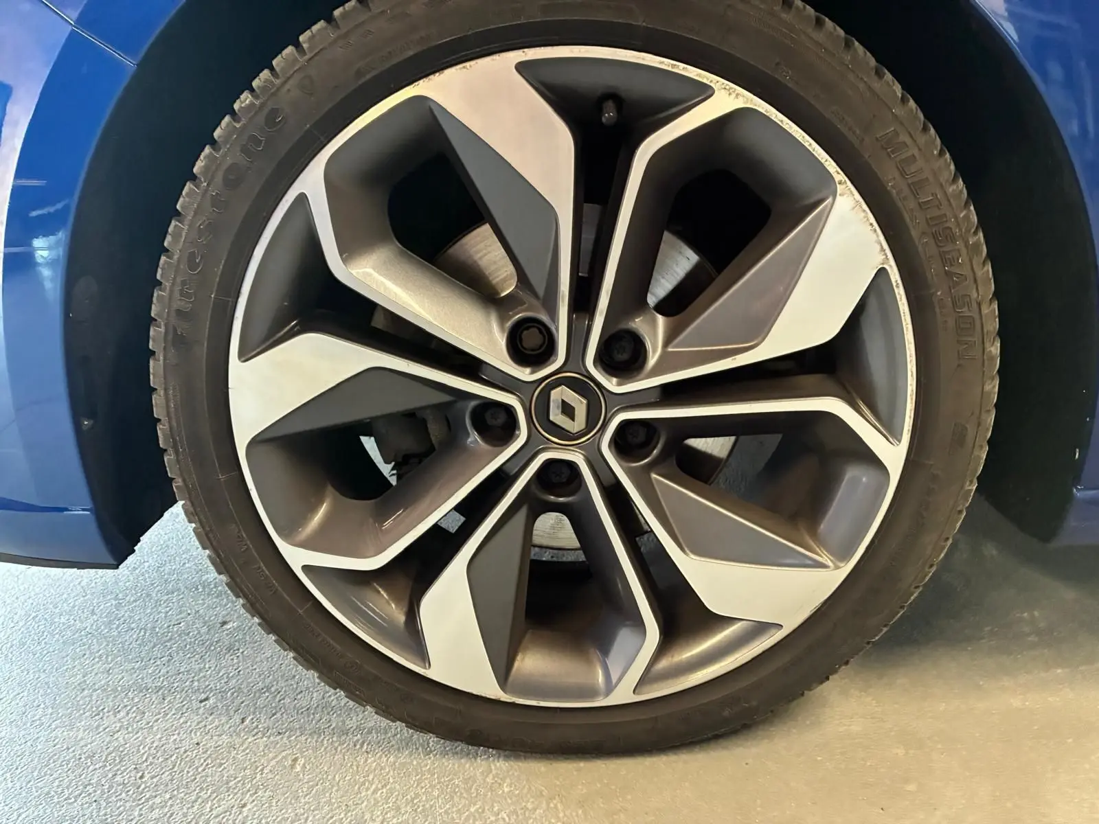 Gros plan sur la jante alliage bicolore grise et argentée d’une Renault Mégane bleu 2019.