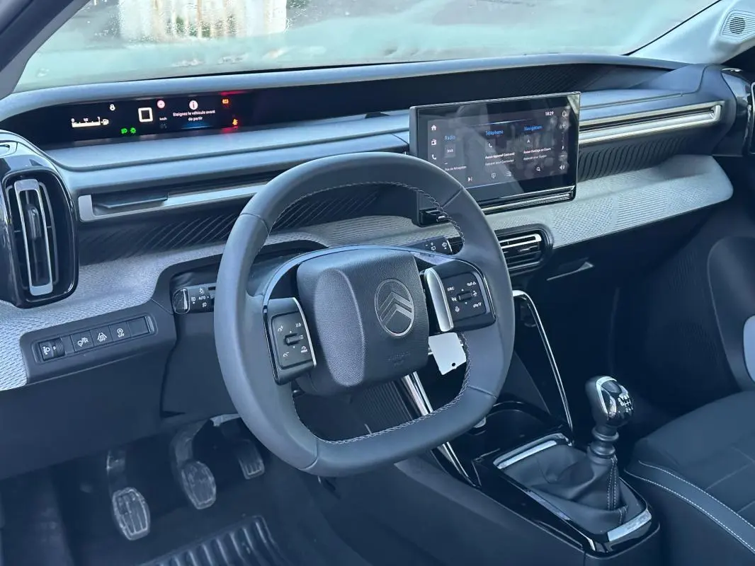 Vue intérieure côté conducteur de la Citroën C3 2025 noire, volant multifonction, écran tactile et levier de vitesses manuel.