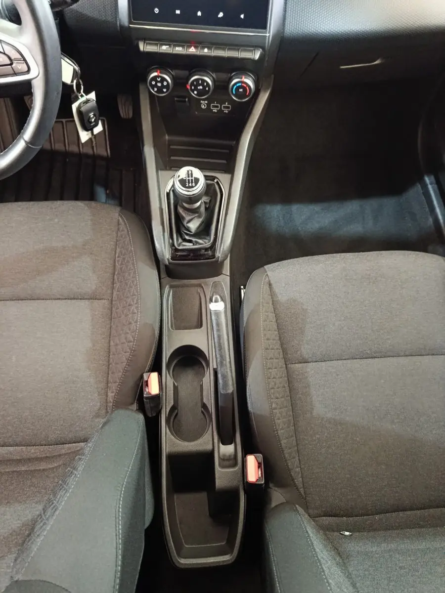Vue intérieure centrée sur la console centrale et levier de vitesse manuel, sièges tissu gris foncé de la Renault Clio Business.