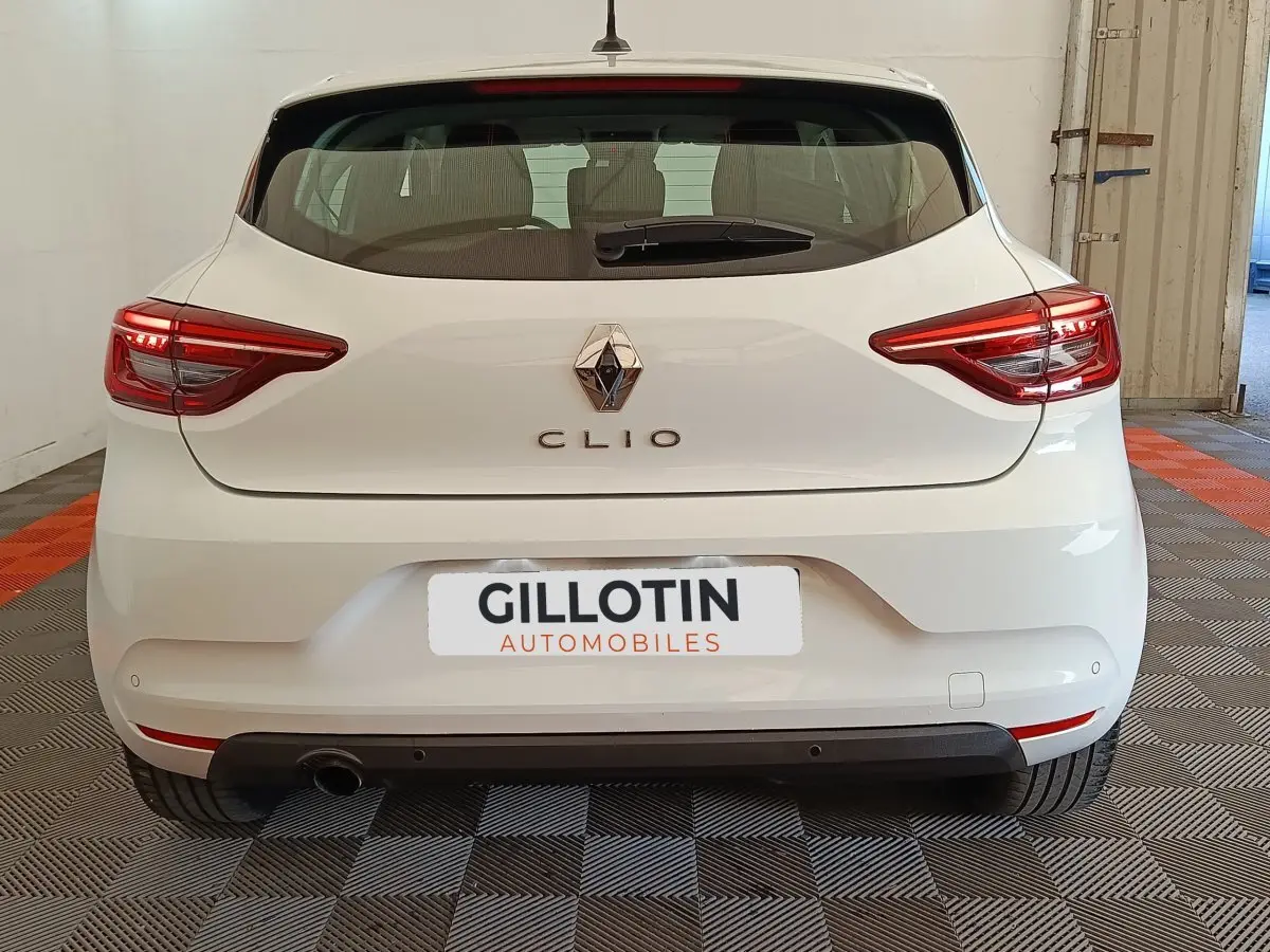 Vue arrière d'une Renault Clio blanche 2022 avec feux LED et logo Renault visible sur un sol damier intérieur.