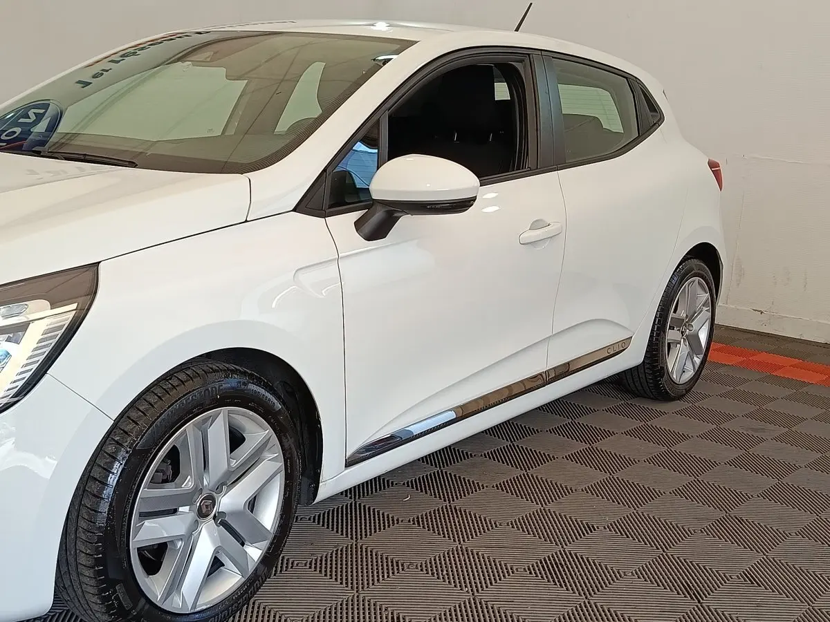 Vue 3/4 avant droit d'une Renault Clio Business Blue dCi 100 blanche avec jantes alliage et rétroviseurs assortis.