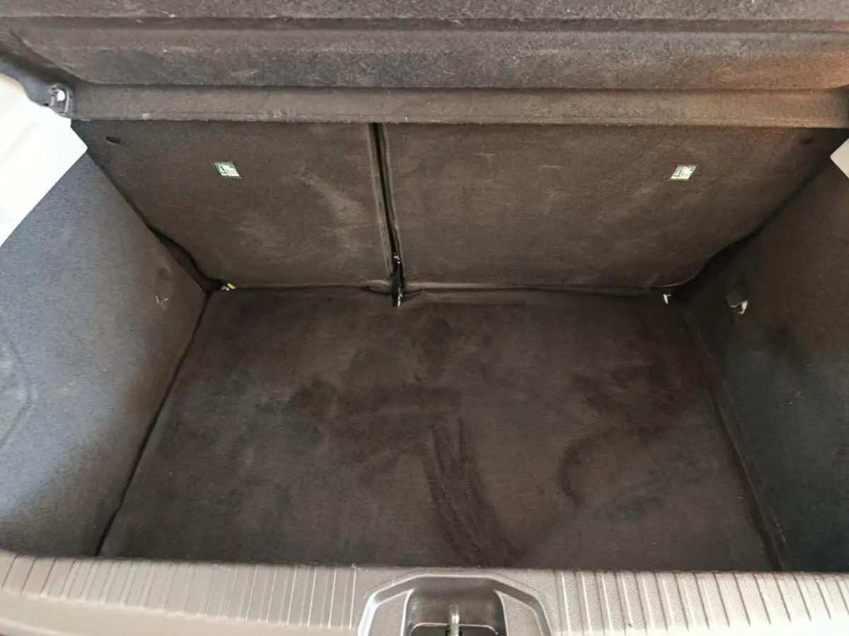Coffre vide de Renault Clio Business Blue dCi 100 blanc, vue intérieure en plongée montrant la moquette noire.