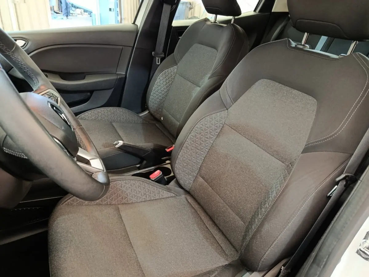 Vue intérieure côté conducteur de la Renault Clio Business Blue dCi 100 2022, sièges tissu gris et volant cuir synthétique.