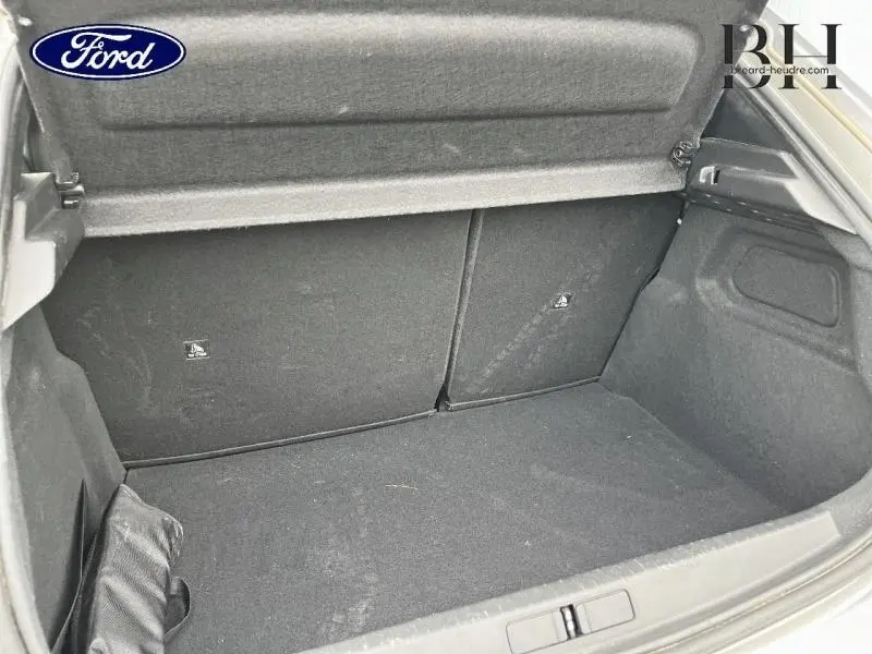 Coffre ouvert vu de l'arrière d'une Peugeot 208 gris Artense, montrant l'espace de rangement et la tablette cache-bagages.