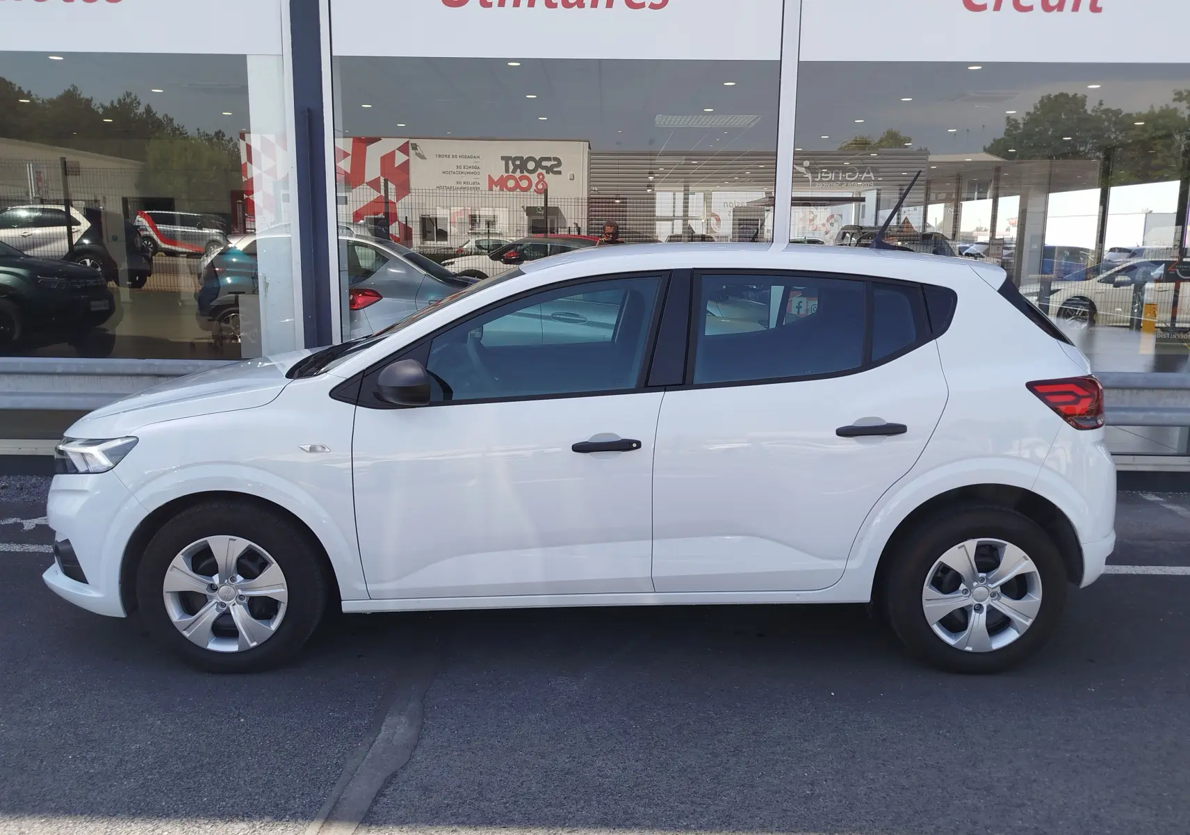 Vue de profil côté gauche d'une Dacia Sandero blanche Glacier 2025, avec jantes alliage et rétroviseurs noirs.