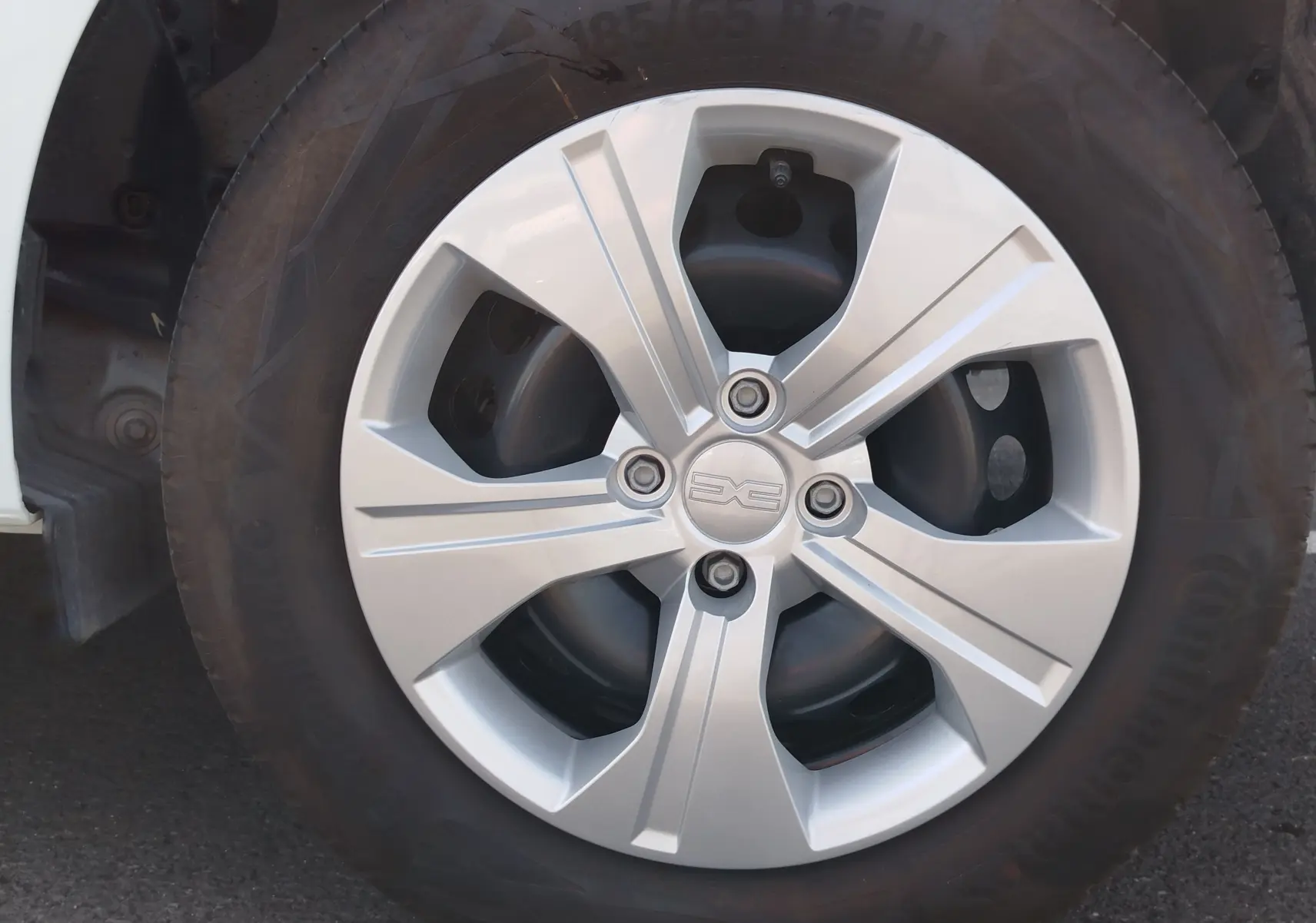 Gros plan sur la roue avant gauche de la Dacia Sandero blanche, mettant en valeur la jante en alliage argentée au design moderne.