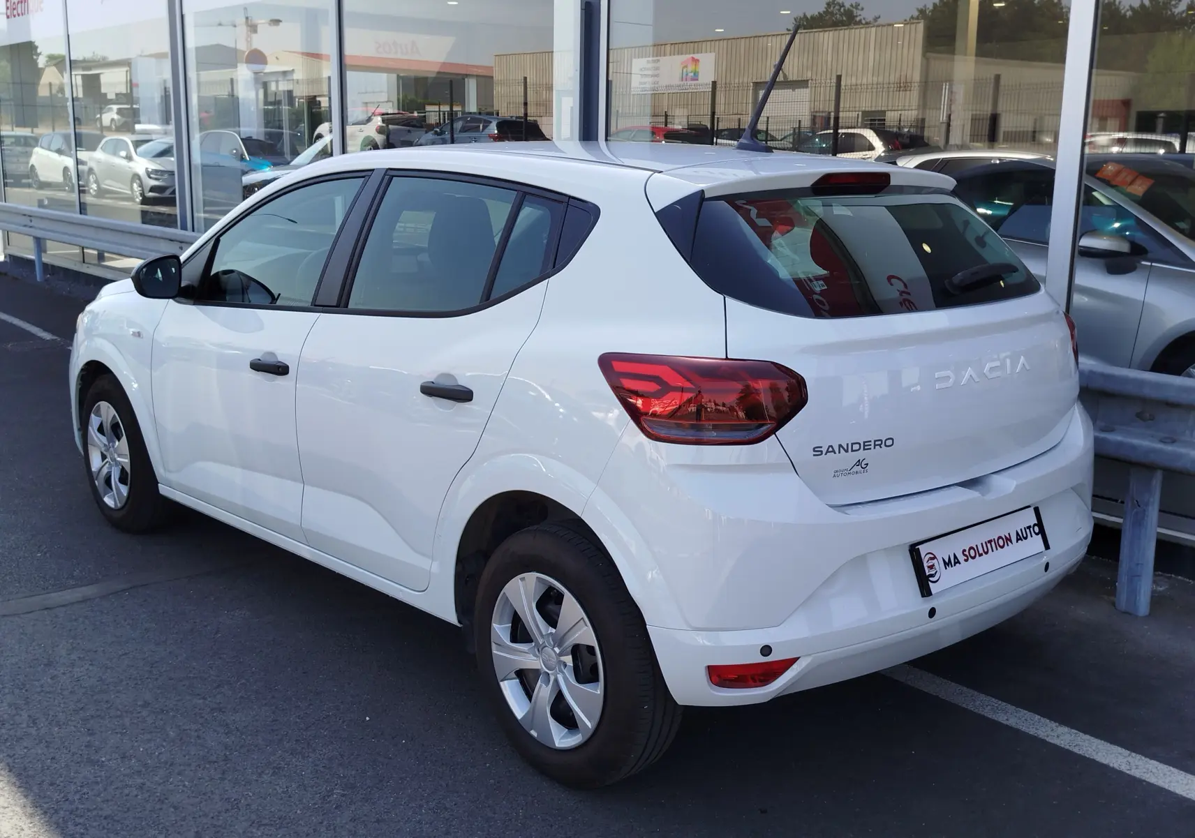 Vue 3/4 arrière droite d'une Dacia Sandero blanche Glacier 2025, avec feux arrière LED et jantes alliage.