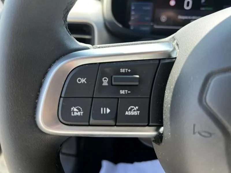 Gros plan sur les commandes au volant gauche du Jeep Avenger blanc 2025, avec boutons de régulateur et assistance.