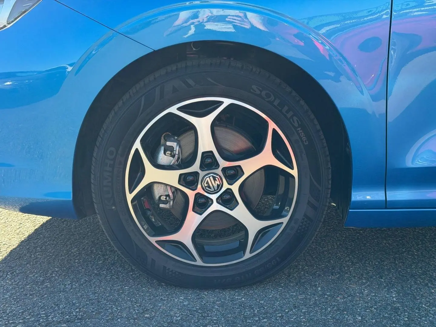Gros plan sur la roue avant gauche de la MG3 1.5 Hybrid+ 195ch Comfort en Como Blue métallisé avec jante alu distinctive.