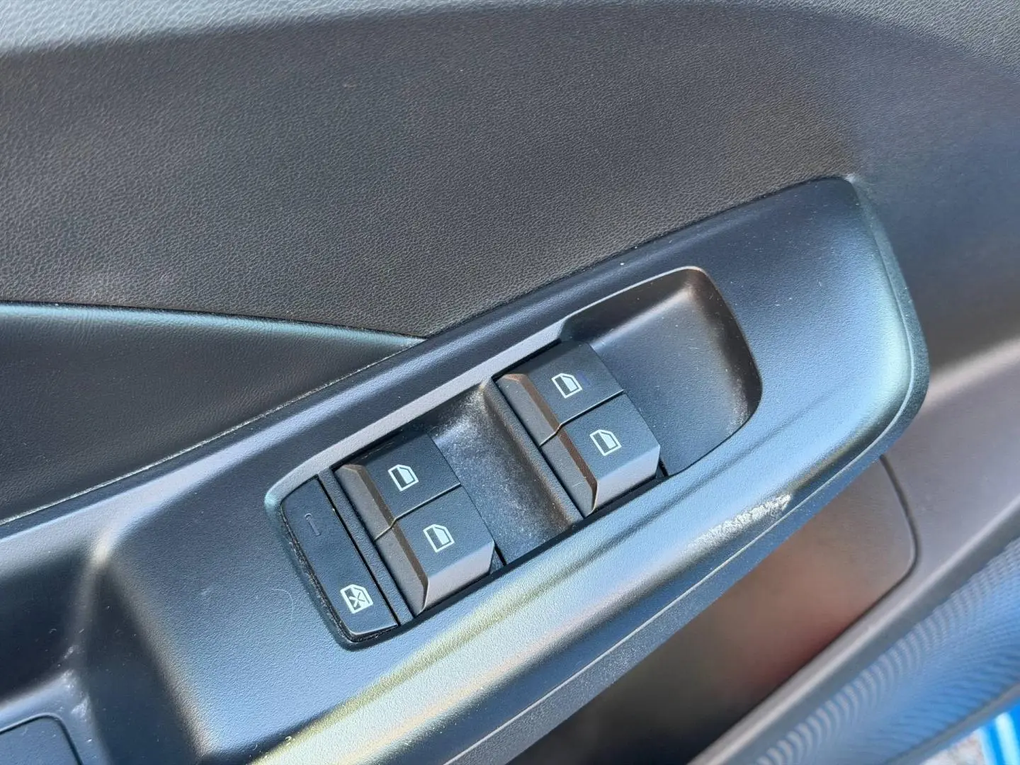 Gros plan sur les commandes des vitres électriques côté conducteur d'une MG3 1.5 Hybrid+ 2025 en Como Blue métallisé.