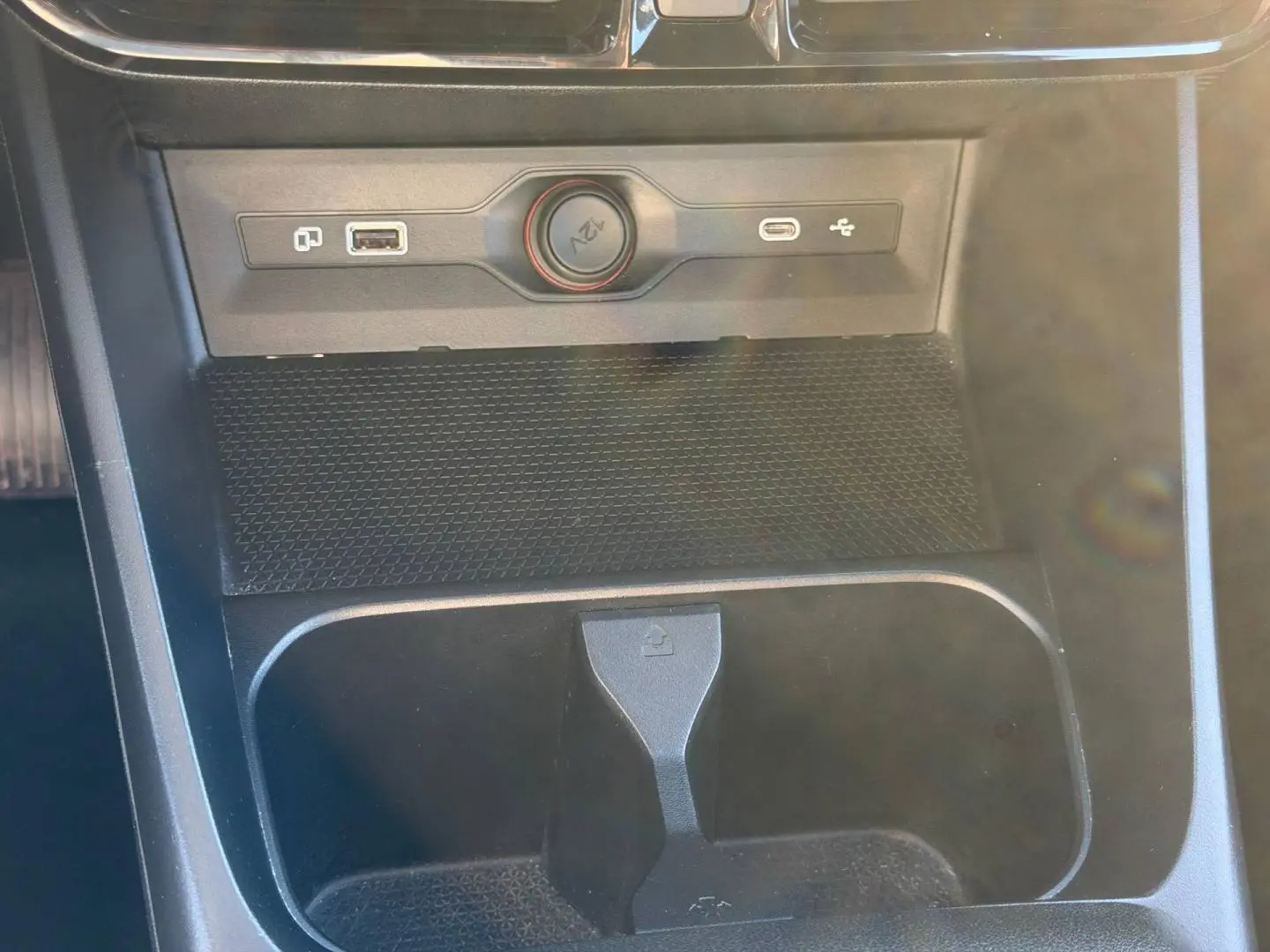 Gros plan sur la console centrale noire du MG3 1.5 Hybrid+ 195ch Comfort, avec prises USB et prise 12V visibles.