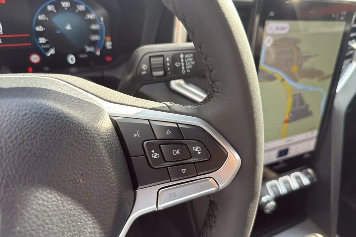 Gros plan sur le volant et les commandes du Volkswagen Amarok Simple Cabine 2025, avec écran tactile et navigation visible.