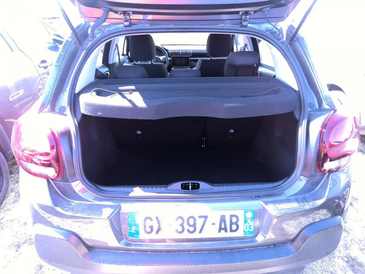 Vue arrière ouverte sur le coffre d'une Citroën C3 gris foncé 2024, avec banquette arrière et intérieur visibles.