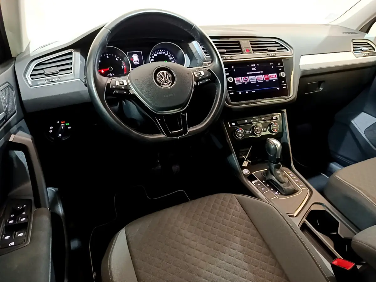 Vue intérieure avant du Volkswagen Tiguan 2020 avec tableau de bord noir, volant cuir multifonctions et écran tactile central.