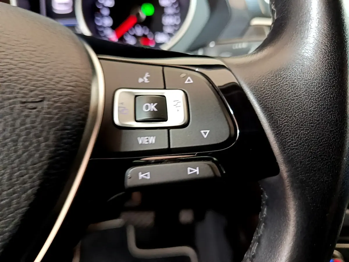 Gros plan sur les commandes gauche du volant cuir noir du Volkswagen Tiguan 2020, boutons multifonctions visibles.