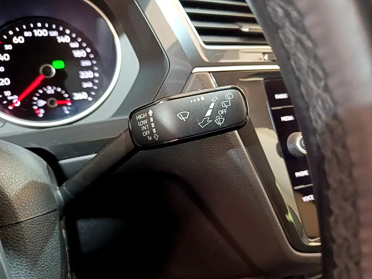 Gros plan sur la manette d’essuie-glace du Volkswagen Tiguan 2020, tableau de bord et volant en cuir visibles.