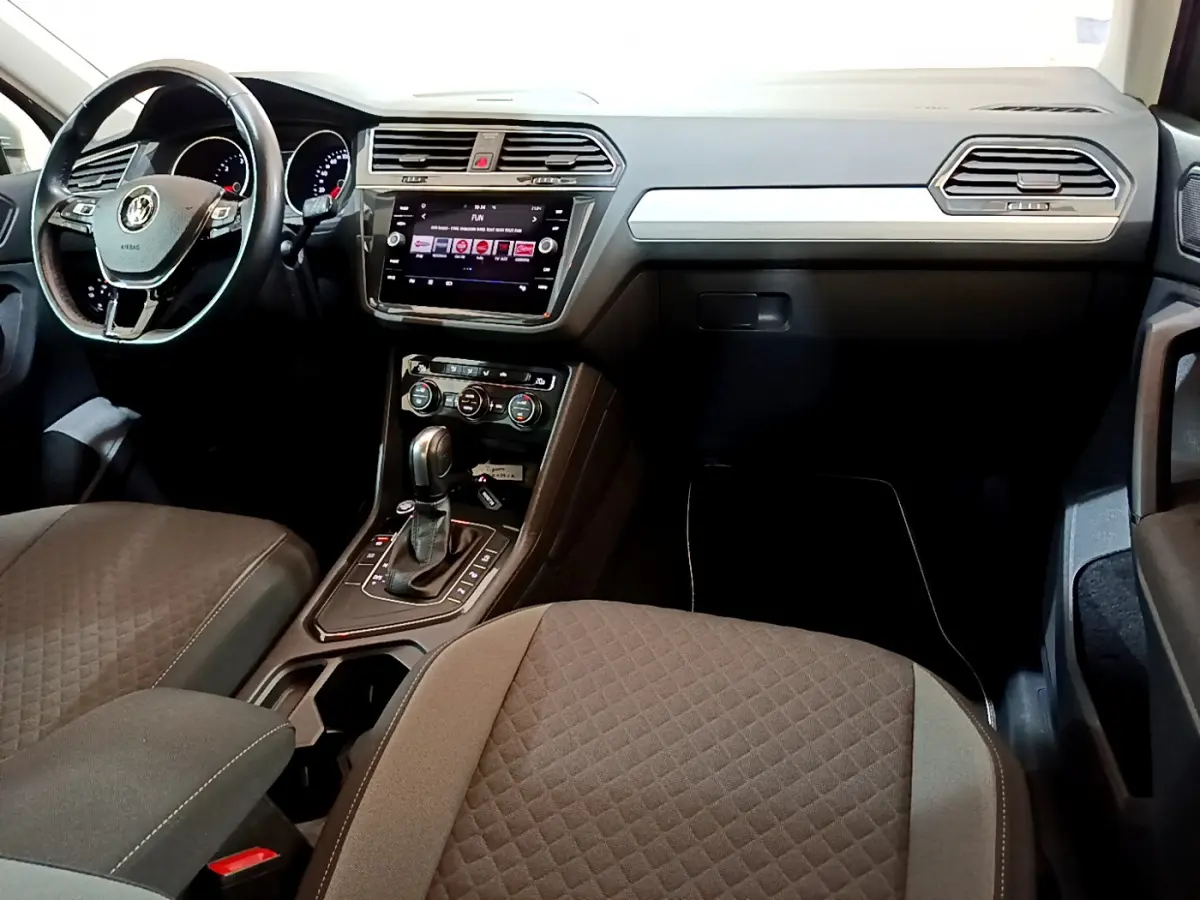 Intérieur du Volkswagen Tiguan 2020, vue du poste de conduite avec volant cuir, écran tactile et console centrale noire.