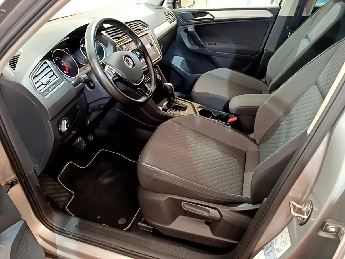 Intérieur avant droit du Volkswagen Tiguan gris clair 2020, sièges tissu gris et tableau de bord avec écran tactile.