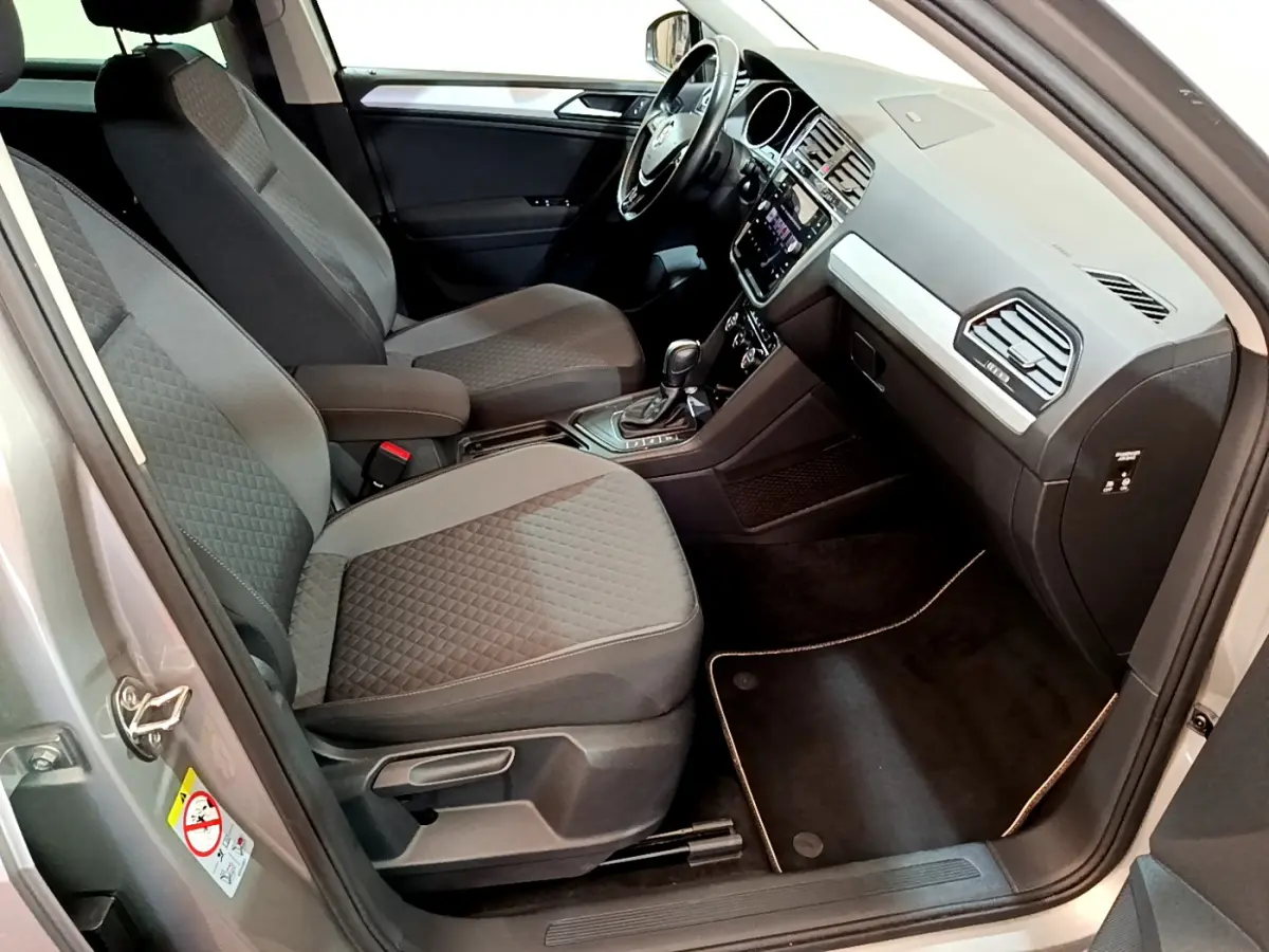 Intérieur avant droit du Volkswagen Tiguan gris clair 2020, sièges tissu gris et tableau de bord avec écran tactile.