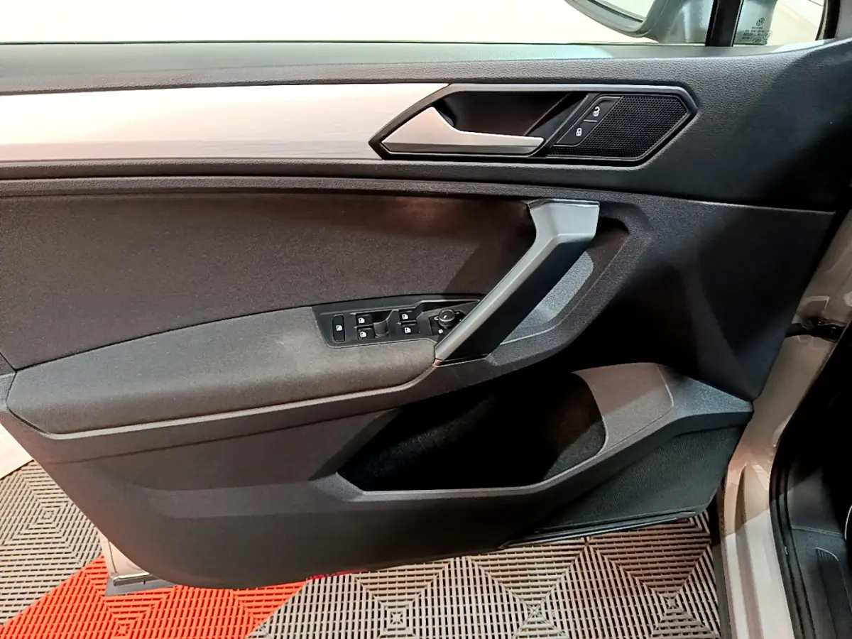 Porte côté conducteur du Volkswagen Tiguan gris clair 2020, avec commandes électriques et insert imitation bois.
