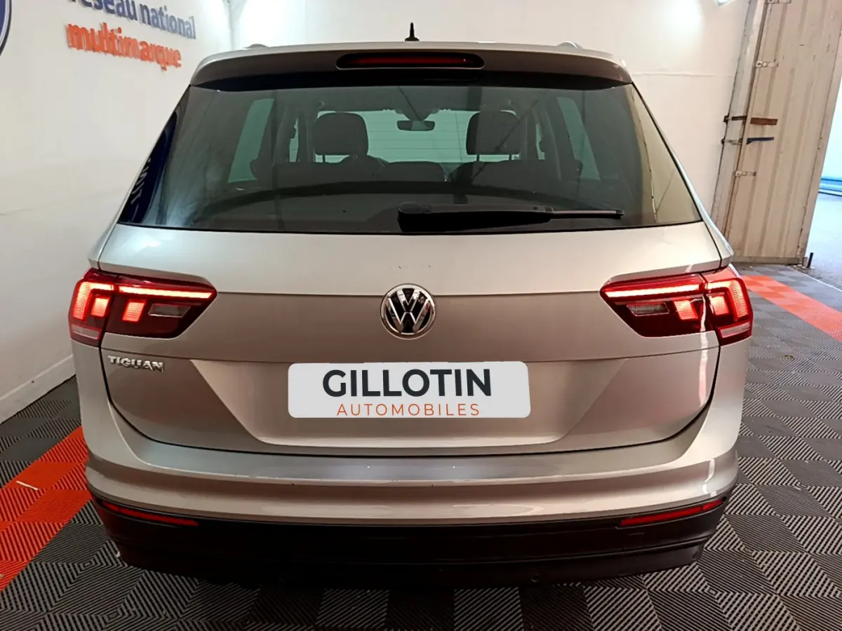Vue arrière d'un Volkswagen Tiguan gris clair 2020 avec feux LED allumés et logo VW visible.