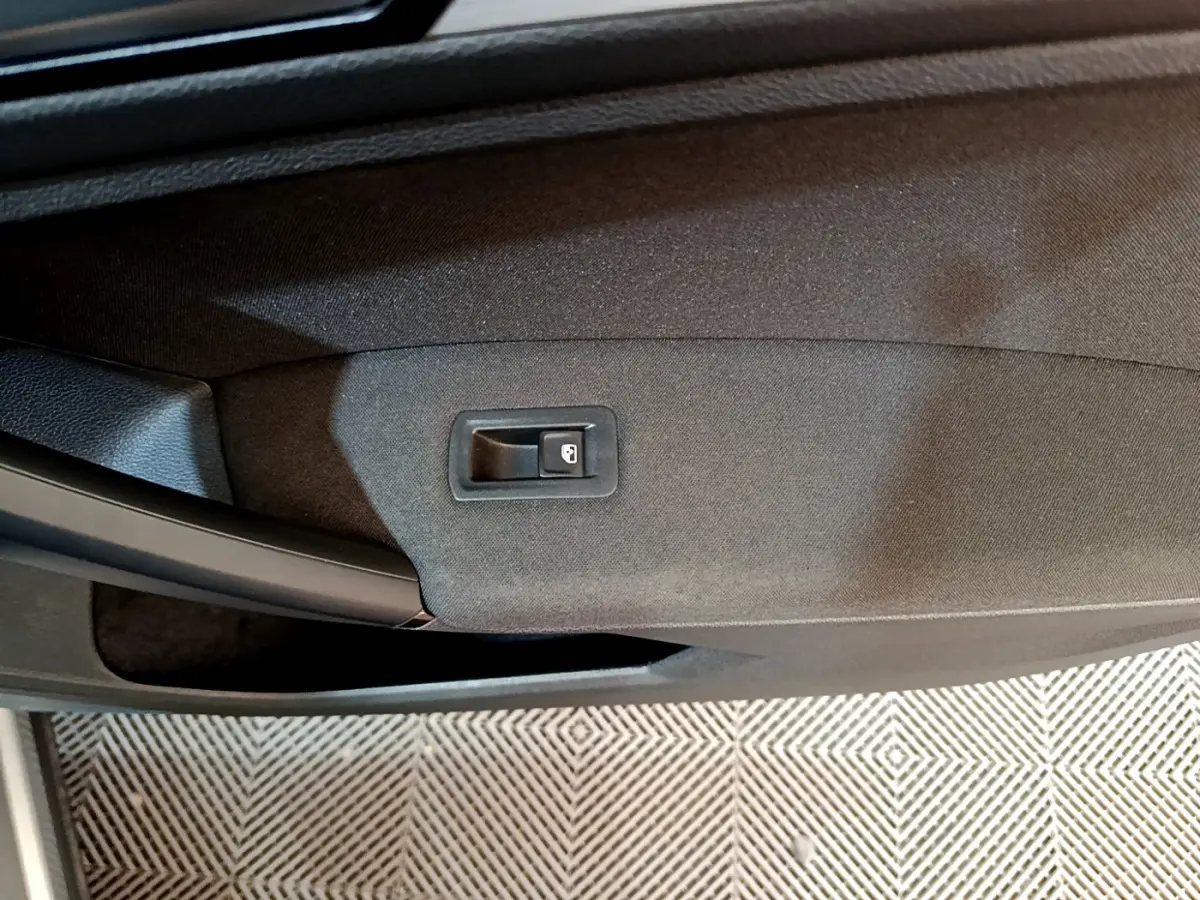 Gros plan sur le bouton de verrouillage de porte intégré dans le panneau de porte noir du Volkswagen Tiguan gris clair.