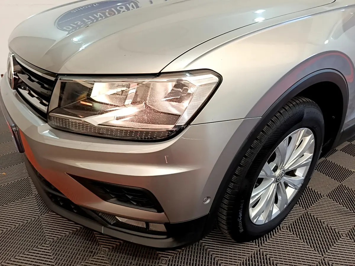 Vue 3/4 avant droit d'un Volkswagen Tiguan gris clair mettant en valeur le phare LED et la jante alliage.