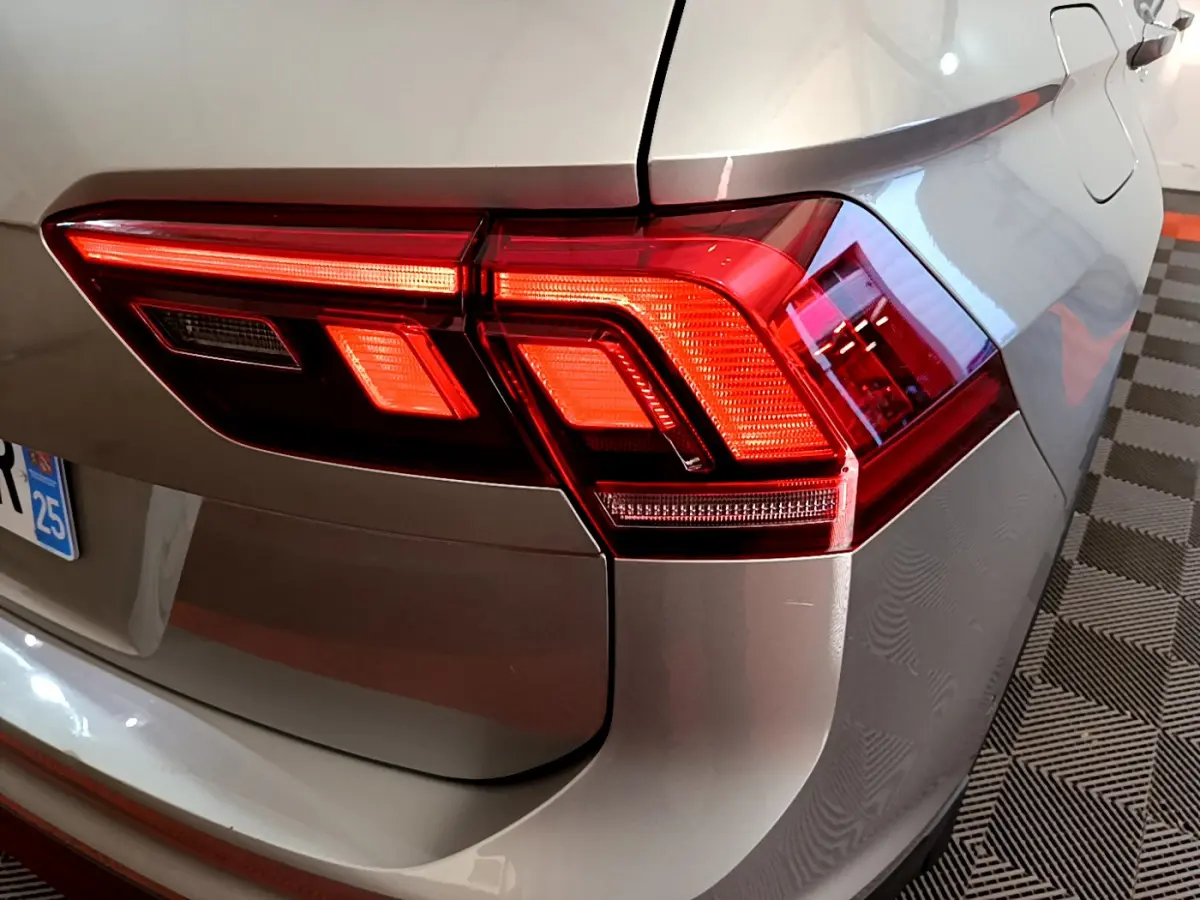 Gros plan sur le feu arrière droit rouge d'un Volkswagen Tiguan gris clair 2020, avec la trappe à carburant visible.