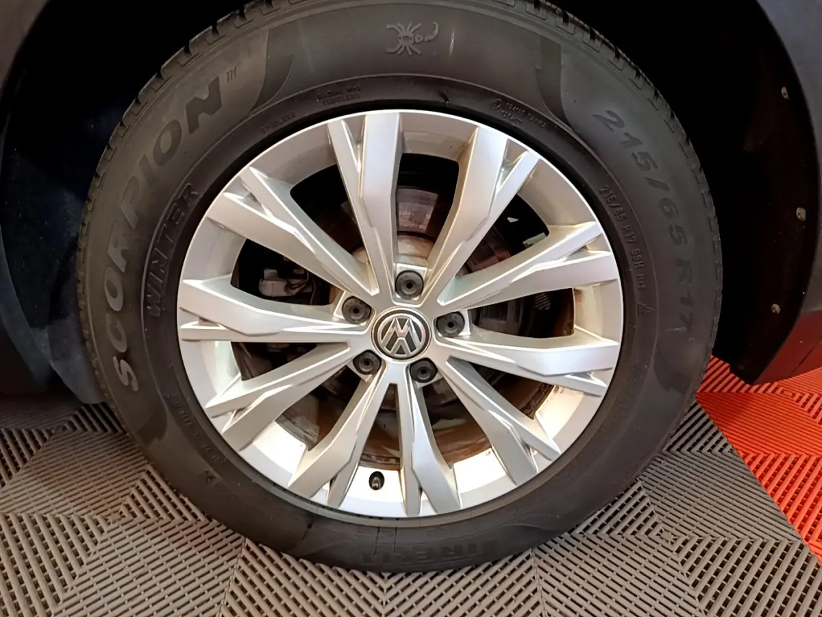 Gros plan sur la jante alliage argentée et pneu hiver Pirelli Scorpion du Volkswagen Tiguan gris clair.