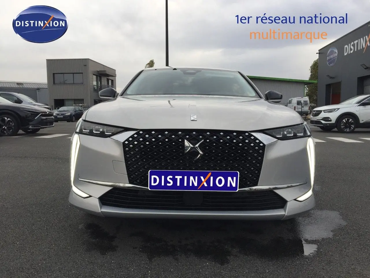Vue frontale d'une DS4 2024 Eph Crystal avec calandre noire et feux LED verticaux allumés sur parking.