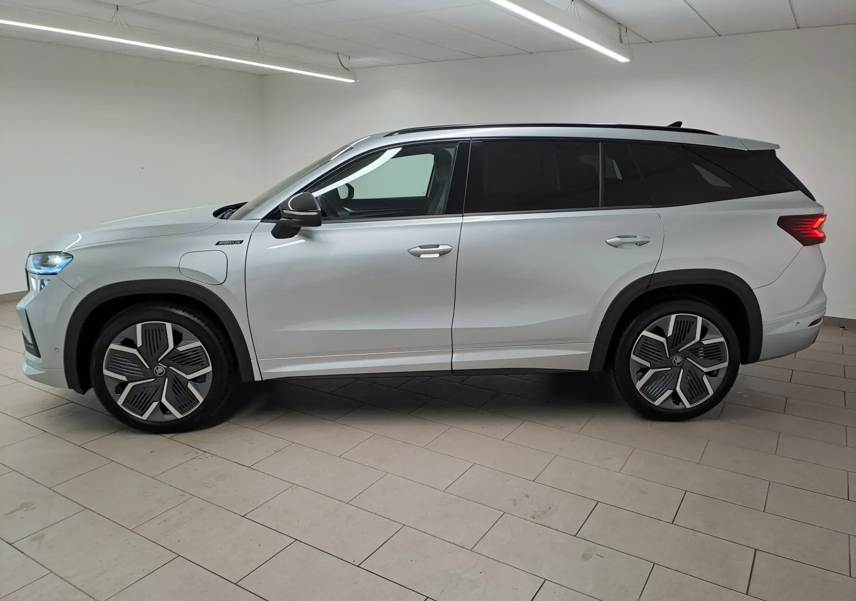 Vue de profil droit du Skoda Kodiaq gris argent 2025 avec jantes alliage 20 pouces et toit noir contrasté.