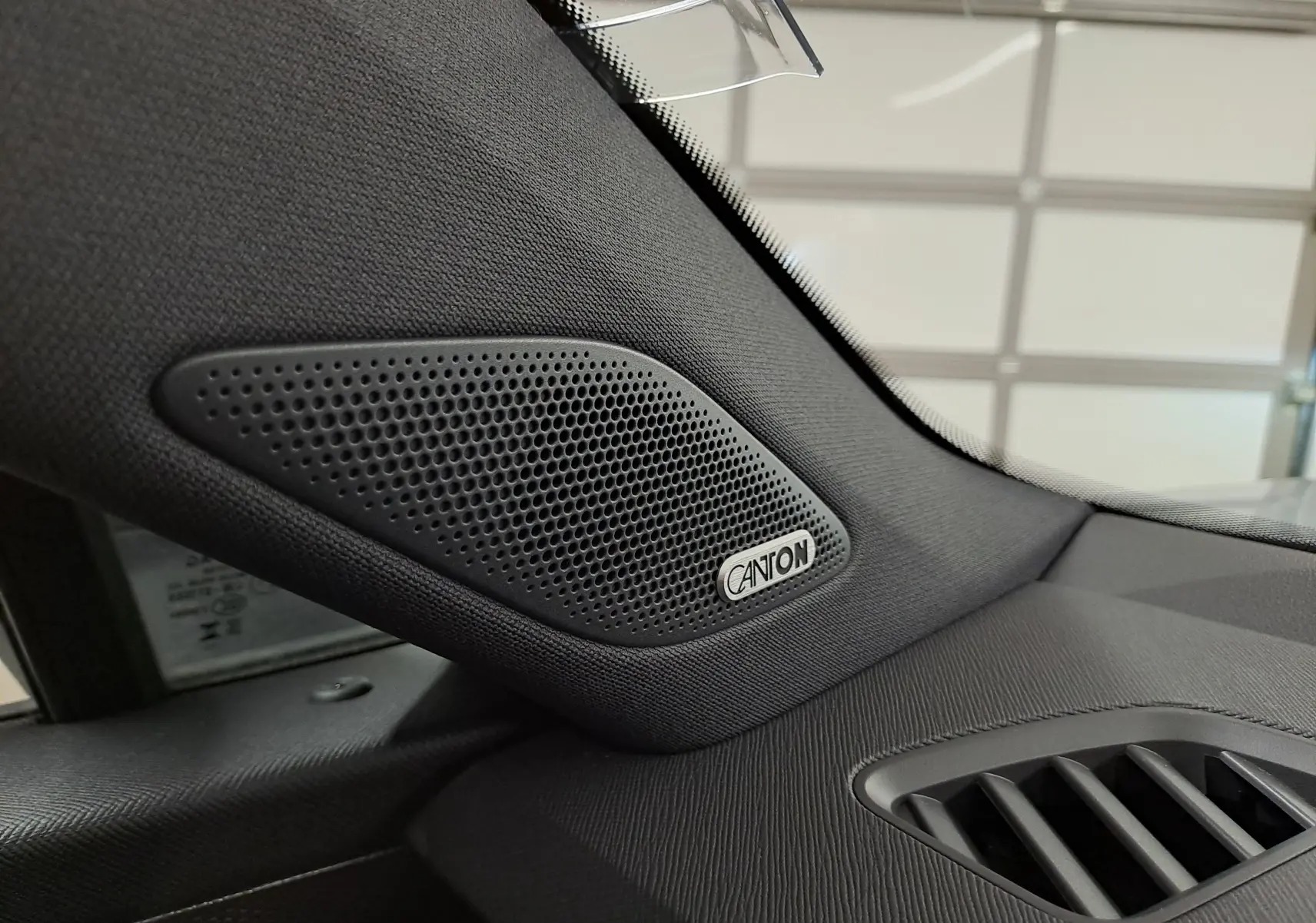 Gros plan sur l'enceinte Canton côté gauche du tableau de bord noir du Skoda Kodiaq gris argent 2025.